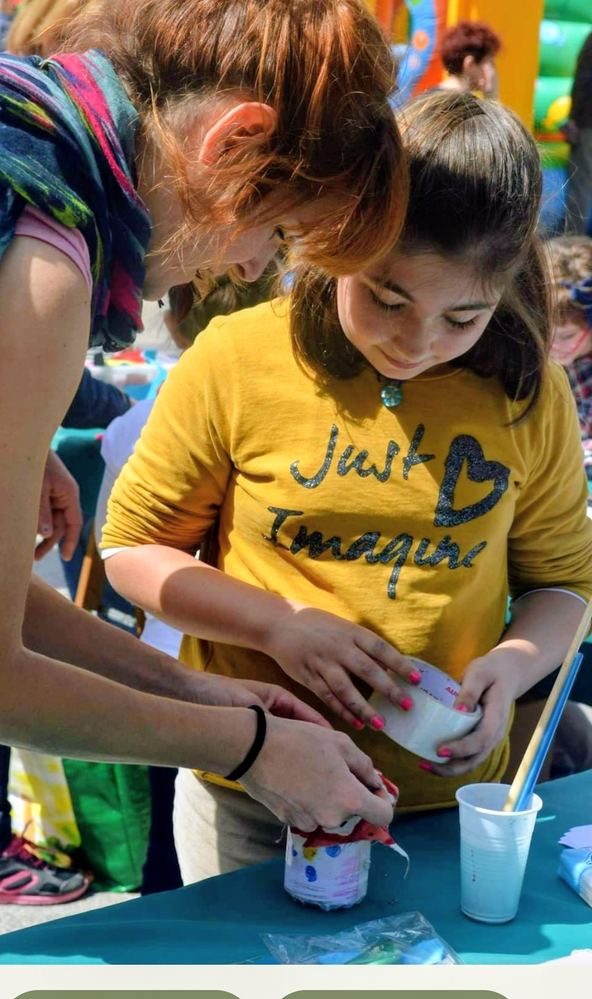 Araceli Lozano acompañando a una niña en un taller creativo al aire libre