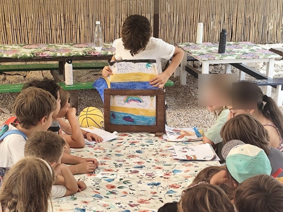 Un niño cuenta con el kamishibai el cuento que ha pintado, mientras el grupo le escucha