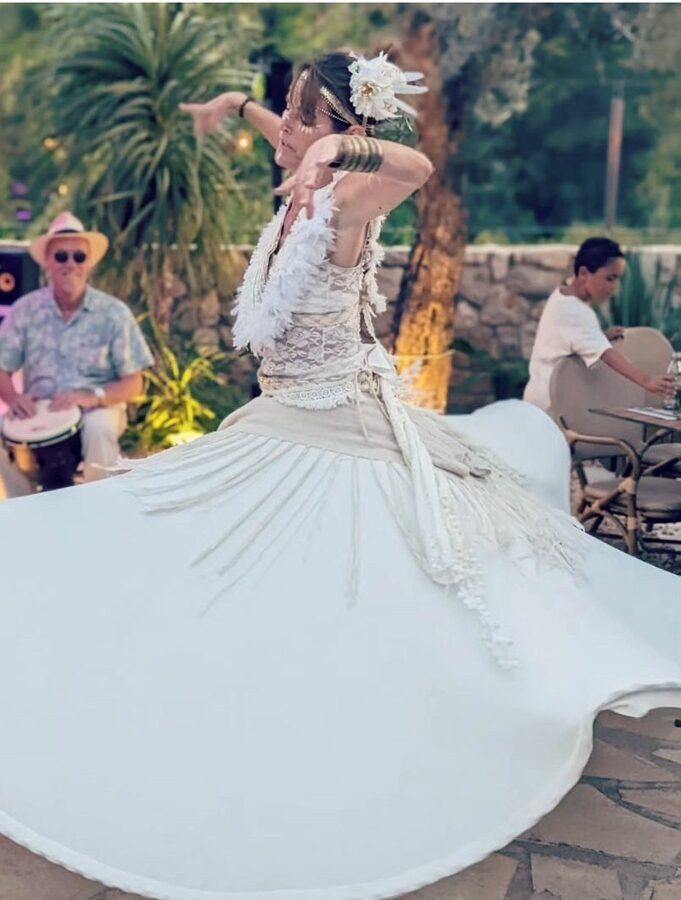 Araceli danzando de blanco, con el vestido en pleno giro, en una actuación al aire libre