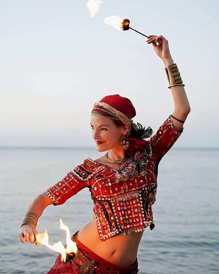 Araceli danzando con fuego junto al mar al atardecer