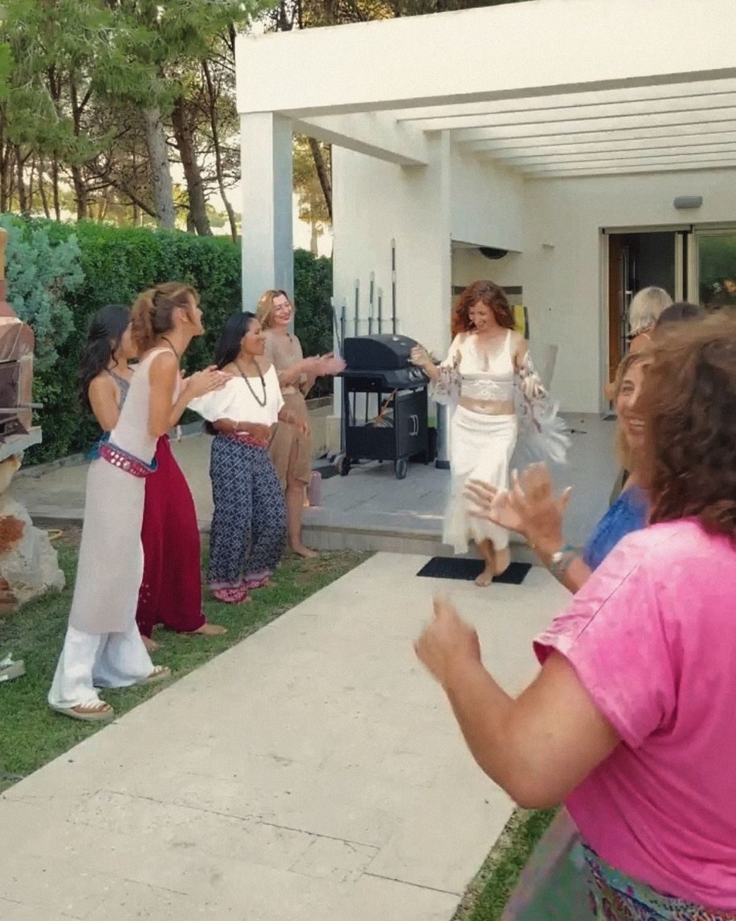 Una mujer baila en el jardín mientras las demás la acompañan con palmas