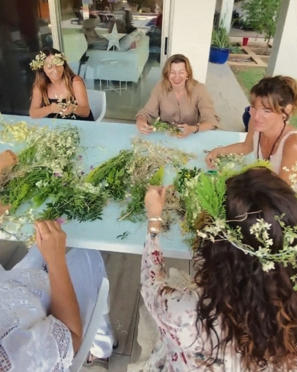 Mujeres haciendo coronas de flores alrededor de una mesa