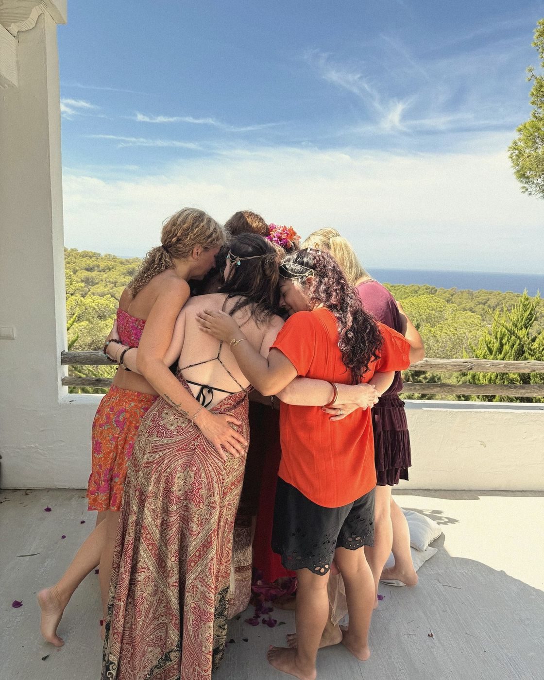 Abrazo de un grupo de mujeres en una terraza con vistas al mar y al pinar
