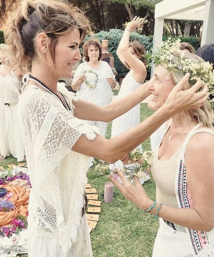 Una mujer corona a otra con flores, entre risas
